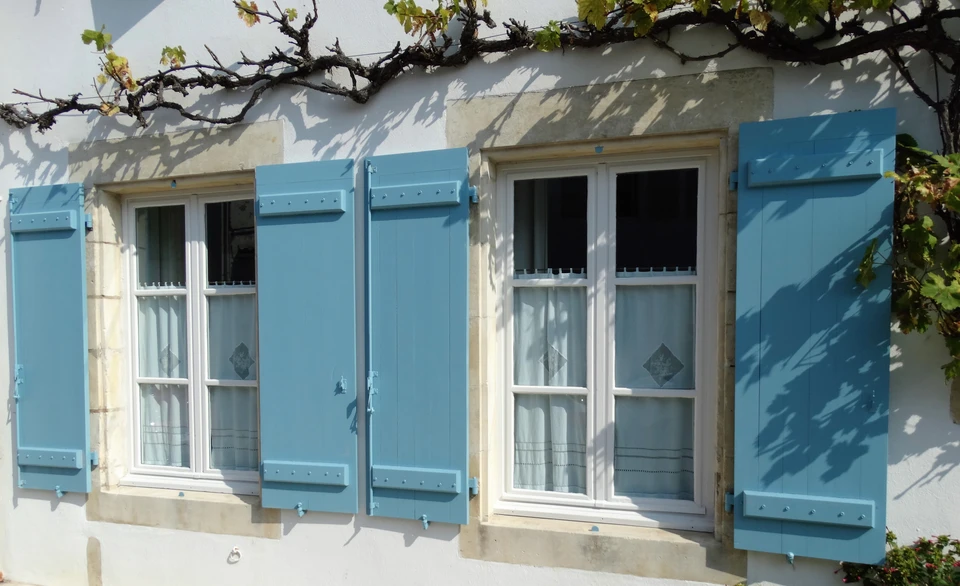 Ouvriers en combinaison orange travaillant depuis une nacelle élévatrice rouge positionnée devant un immeuble moderne