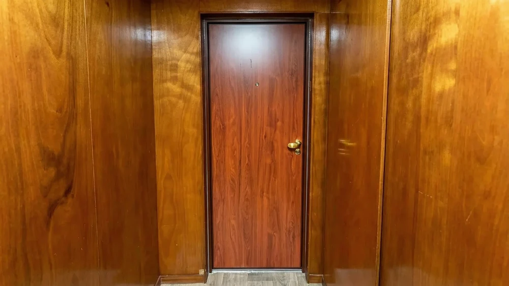 Entrée résidentielle moderne avec porte grise à panneau vitré, mur façade rose texturé, auvent métallique blanc