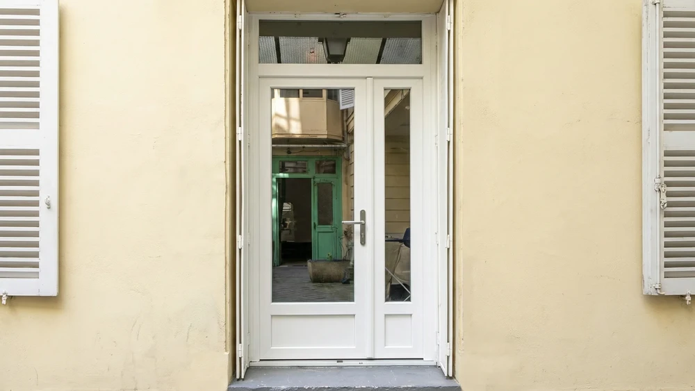 Entrée principale d'une maison résidentielle avec double porte en bois blanc à panneaux moulurés et vitraux décoratifs circulaires