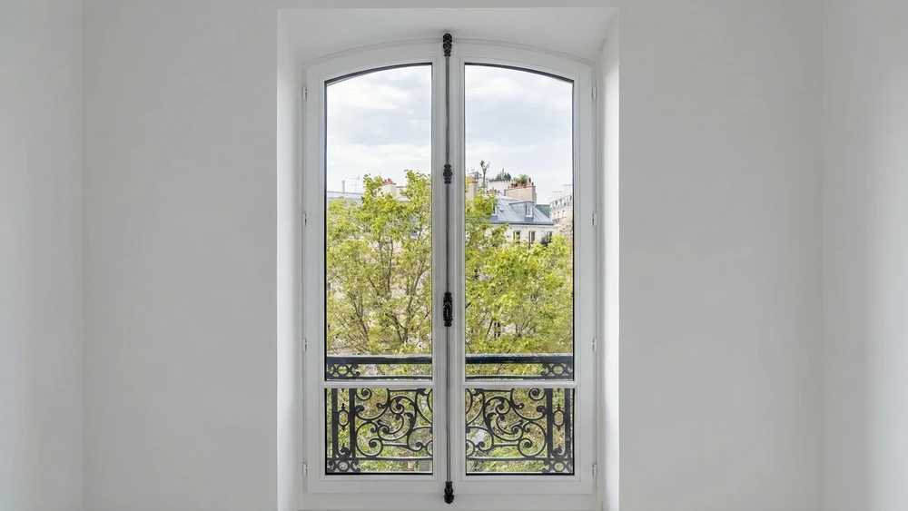 Intérieur moderne avec fenêtre à double battant en PVC noir, grilles géométriques, vue sur ciel bleu