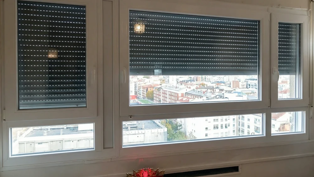 Façade extérieure d'immeuble résidentiel moderne avec volets roulants métalliques gris foncé sur fenêtres rectangulaires