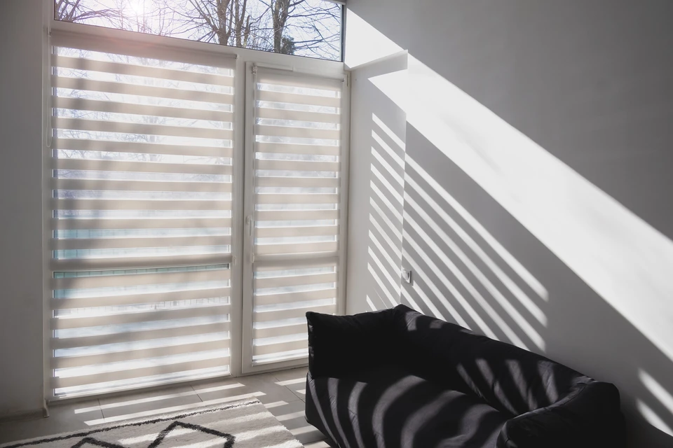 Intérieur minimaliste baigné de lumière naturelle filtrée par store bambou